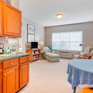 A cozy apartment interior featuring a small kitchen area and a comfortable living space with natural light.