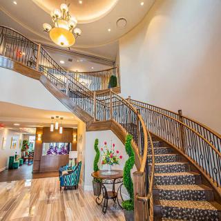 Elegant lobby with a grand staircase and chandelier.