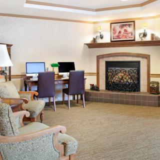 A cozy living room featuring a fireplace and an office area with computers.