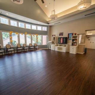 A spacious room with hardwood flooring, large windows, and modern lighting.