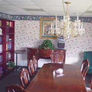A classic dining room with a wooden table, chandelier, and bookshelf.