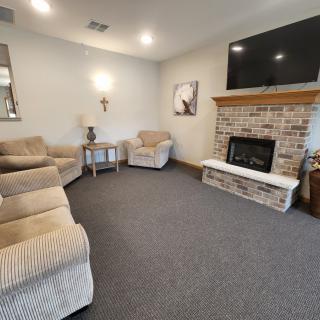 A cozy living room featuring a brick fireplace, comfortable seating, and a mounted TV.