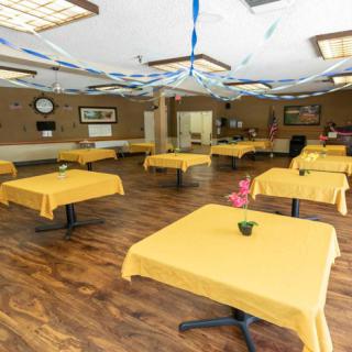 A decorated dining room with yellow tablecloths and wooden flooring.