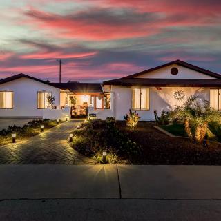 A beautifully lit house at sunset with a landscaped driveway.