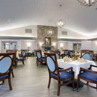 A well-decorated dining room featuring elegant seating and a central stone fireplace.