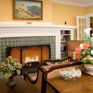 A cozy living room with a fireplace, elegant furniture, and vibrant floral arrangements.