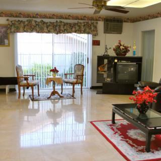 A cozy living room featuring a television, table with chairs, ceiling fan, and vibrant decor.