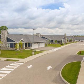 A view of a suburban residential area featuring modern homes and well-maintained landscaping under a cloudy sky.