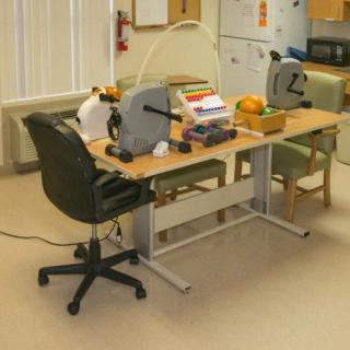 An office workspace with a desk, chairs, and various equipment.