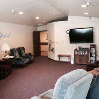 A cozy living room with a television, comfortable seating, and carpeted flooring.