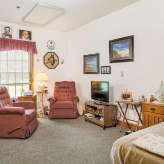 A cozy living room with armchairs, a television, and various wall decorations.