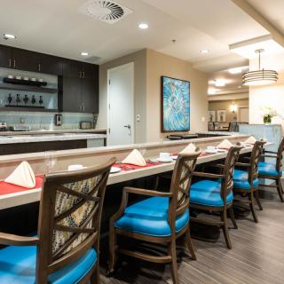 A stylish and modern bar area with blue-cushioned chairs and a sleek countertop.