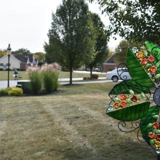 A suburban front yard featuring a colorful decorative object with trees and a street in the background.