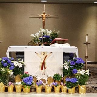 A beautifully adorned altar featuring floral arrangements and a crucifix, set for a religious ceremony.