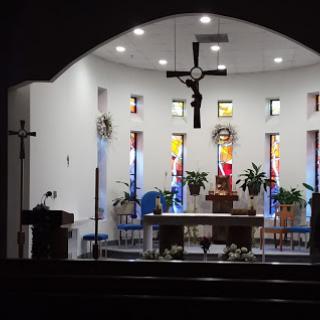 Interior view of a church featuring an altar and colorful stained glass windows.