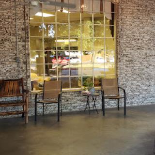 A cozy cafe interior featuring wooden seating and a large window with a brick wall backdrop.