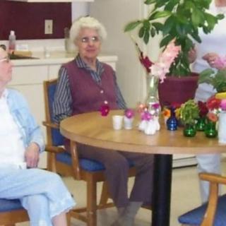 A group of elderly individuals sitting around a table decorated with flowers.