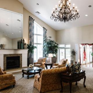 A luxurious living room with elegant furnishings, a grand chandelier, and large windows.