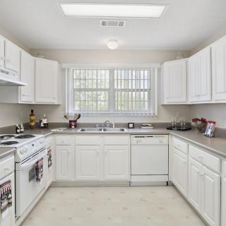A spacious kitchen with white cabinets and modern appliances.