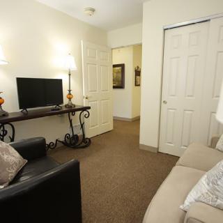 A cozy living room with a sofa, television, and decorative lamps.