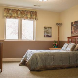 A cozy bedroom with a neatly made bed and natural light coming through the window.