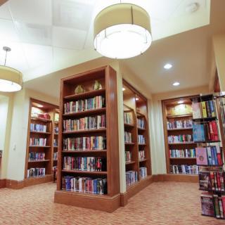 A well-lit library interior showcasing wooden bookshelves filled with books.