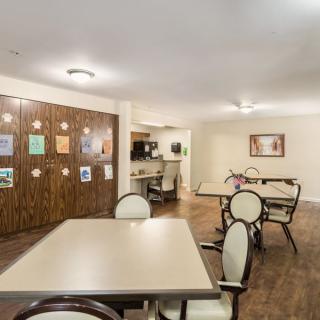 A well-lit dining area with tables and chairs arranged neatly on a wooden floor.