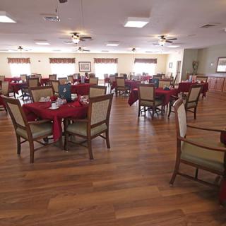 An empty dining area with neatly arranged tables and chairs on a wooden floor.