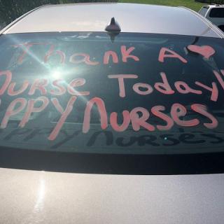 A car window with a message thanking nurses, written in pink letters.