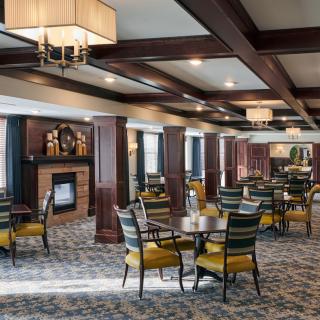 A spacious dining area with elegantly arranged tables and chairs, featuring warm lighting and wooden decor accents.