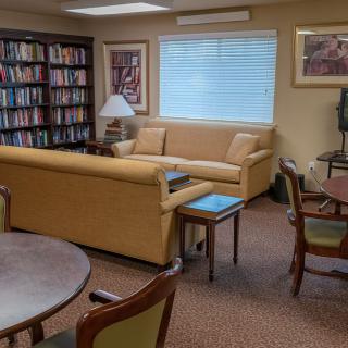A cozy reading area with bookshelves, sofas, and tables.