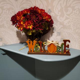 Autumn-themed home decor featuring a bouquet of flowers and a welcome sign with a pumpkin motif.
