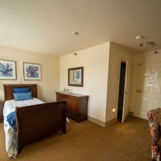 A cozy bedroom featuring a wooden bed, dresser, and decorative artwork on the walls.