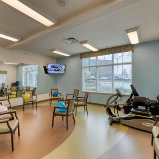 A physical therapy room with exercise equipment and seating.