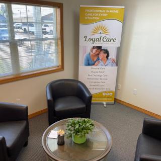 A cozy waiting area featuring comfortable chairs and a banner for Royal Care.