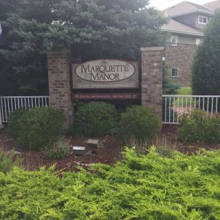 Entrance sign for Marquette Ridge with surrounding greenery.