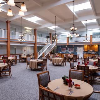 A spacious dining hall with multiple tables, chandeliers, and a modern interior design.