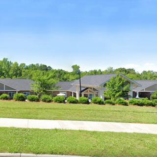A suburban house with a large front lawn and surrounding trees.