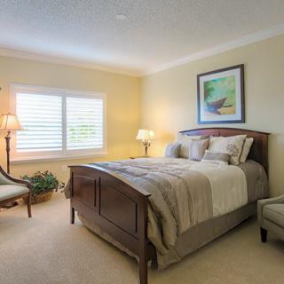 A cozy and well-lit bedroom with a comfortable bed, elegant lamps, and tasteful decor.