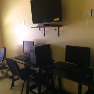A small office space with two computer workstations and a wall-mounted television.