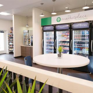 A modern cafe interior featuring a seating area and refrigerators stocked with various snacks and beverages.