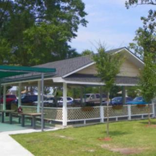 A small pavilion in a park area with surrounding trees and parked cars.