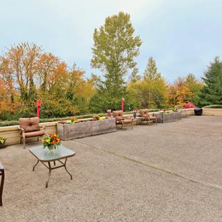 A spacious outdoor patio with furniture set against an autumn landscape of colorful trees.