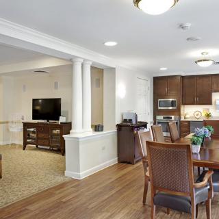 A modern open-concept living and dining area with a connected kitchen, featuring wood flooring and elegant furniture.