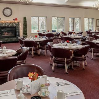 A neatly arranged dining room with round tables and chairs, featuring elegant decor.