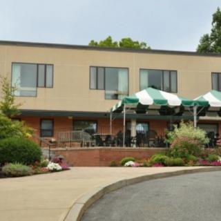 A building with green and white awnings, surrounded by landscaping and a paved driveway.