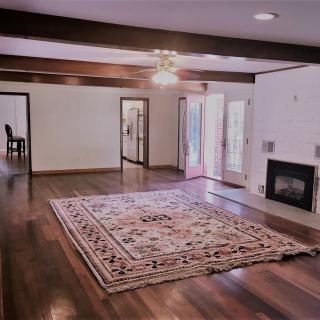 Spacious living room with hardwood floors, a central area rug, and a cozy fireplace.