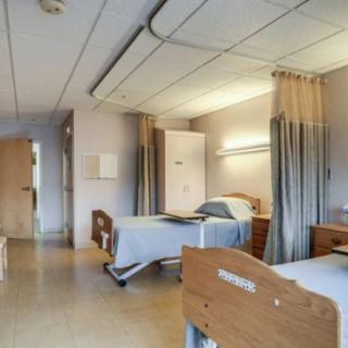A clean and organized hospital room with two beds separated by a curtain.