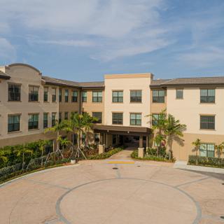 A three-story building with a welcoming entrance surrounded by landscaping.
