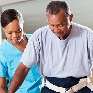 A healthcare professional assists an elderly person during a physical therapy session.